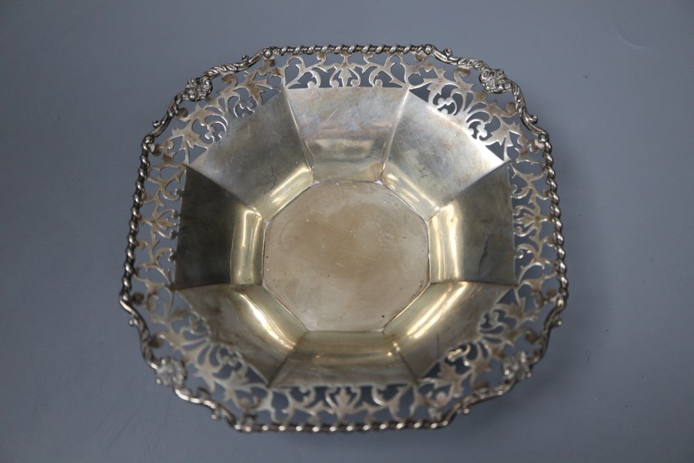 An Edwardian silver sugar basket, George V silver bon-bon dish, silver mounted match strike and a mug salt and spoon (4)